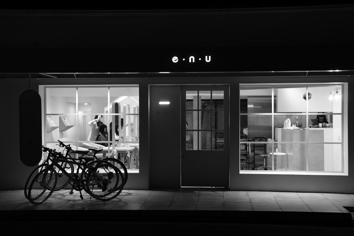 Vitrine d'un magasin avec vélos garés à l'extérieur, éclairage sombre.