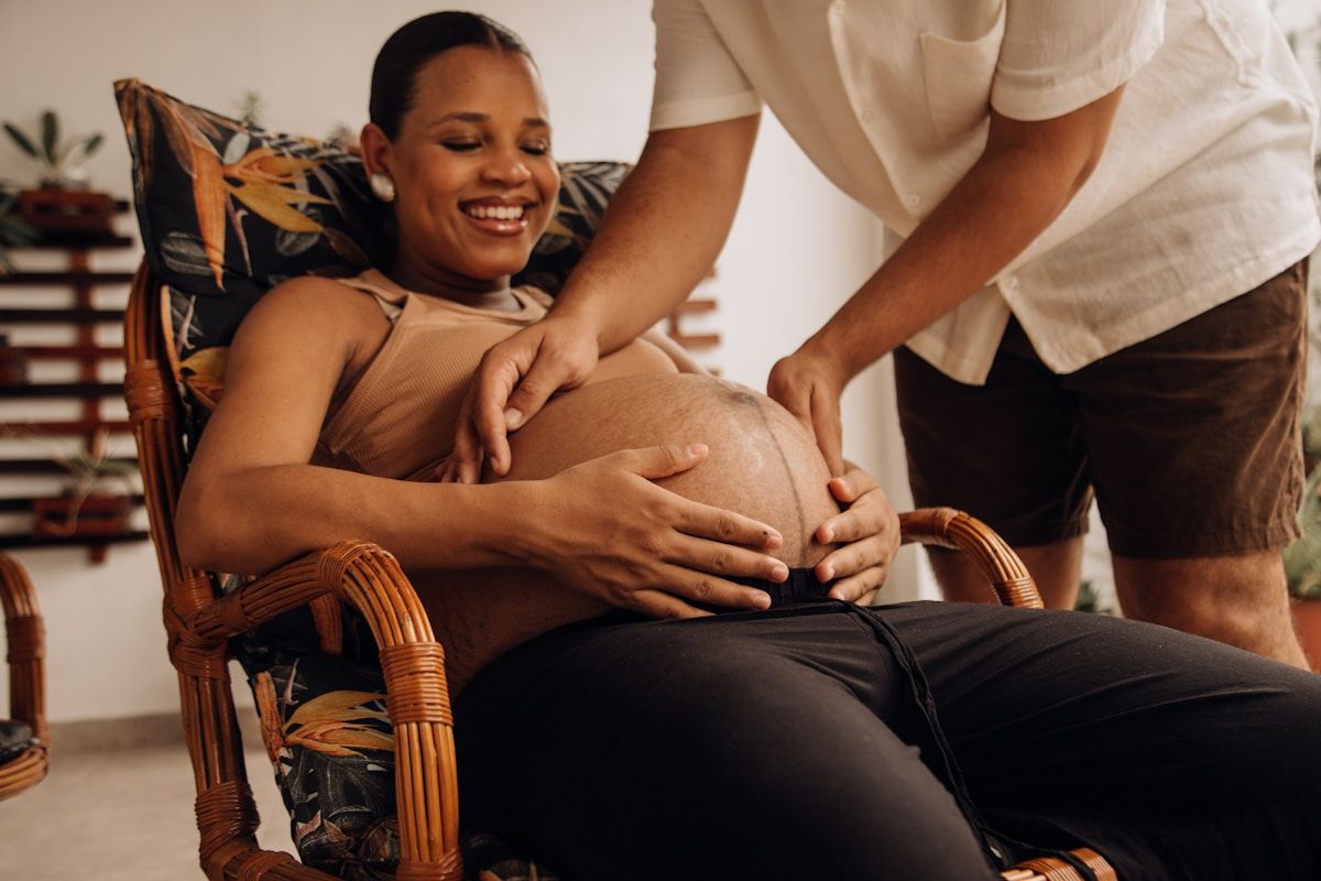 Femme enceinte souriante assise dans un fauteuil en rotin.