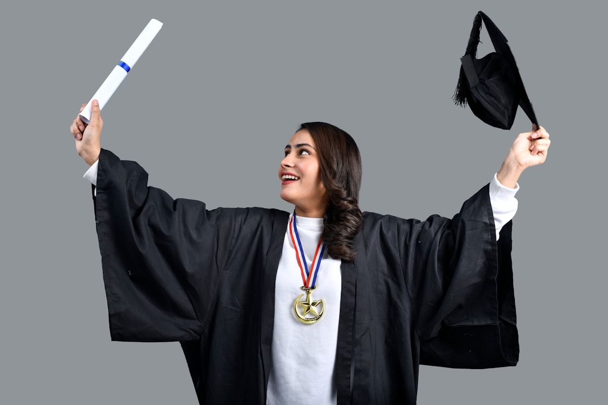 Femme diplômée en robe de graduation, tenant un diplôme et une médaille.