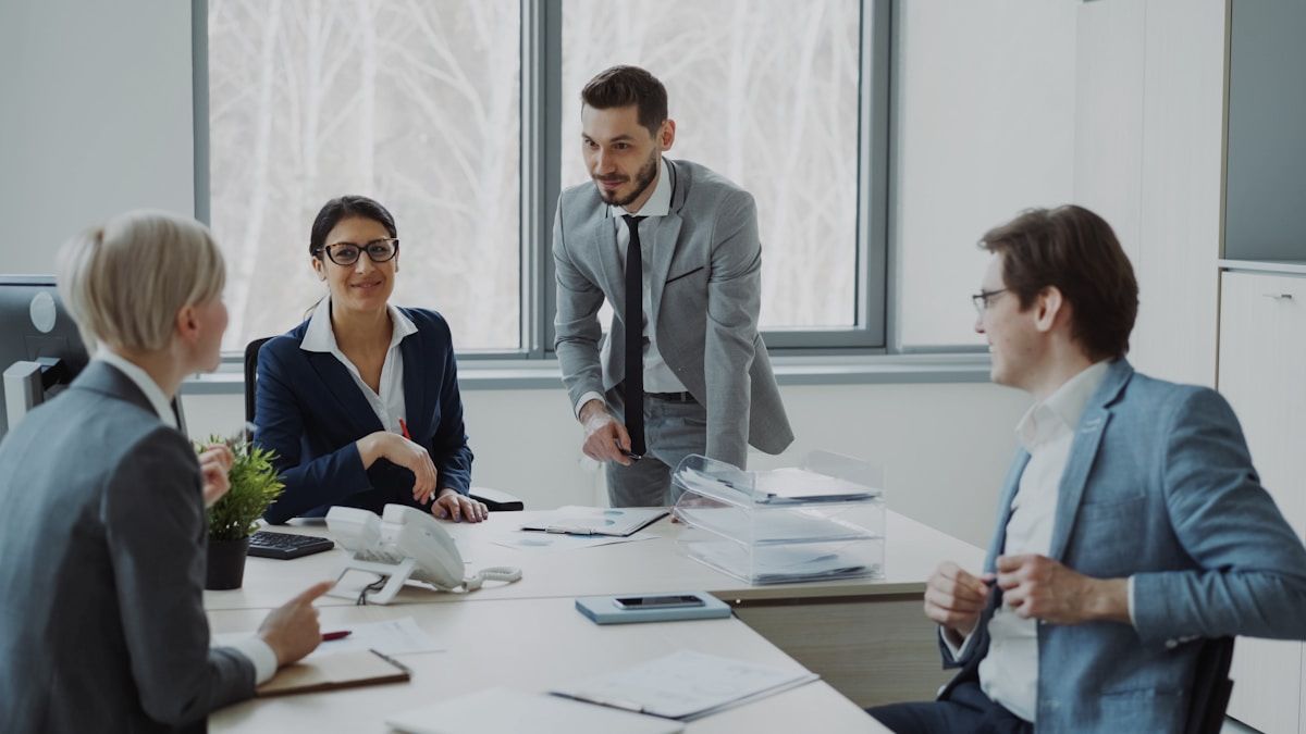 Réunion d'affaires avec des professionnels en costume dans un bureau moderne.