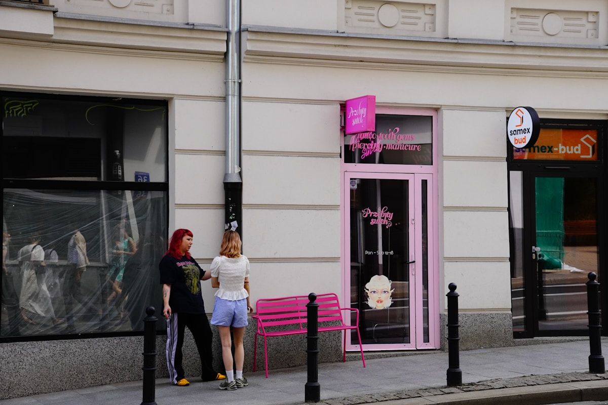 Deux personnes debout devant un salon de beauté rose vif.