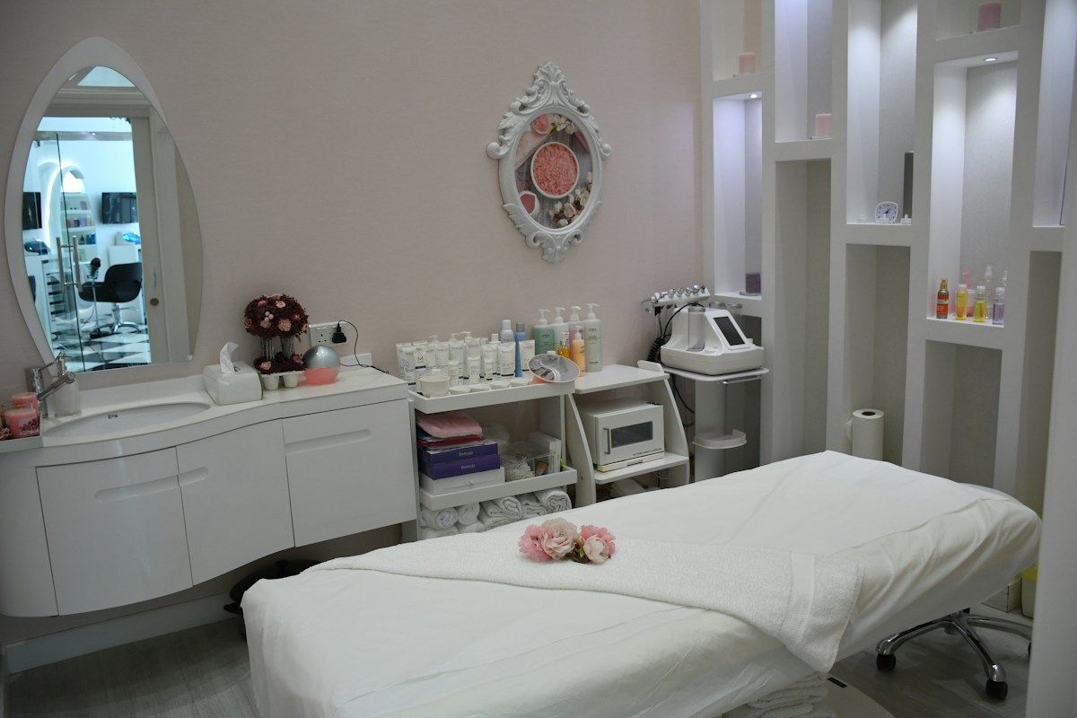 Salle de soins esthétique blanche avec table et produits.