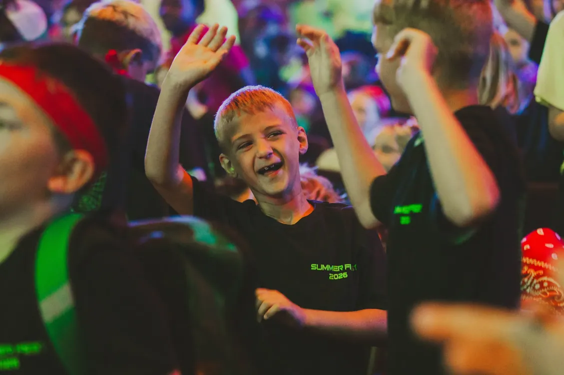 Boy raising his hand and smiling during worship