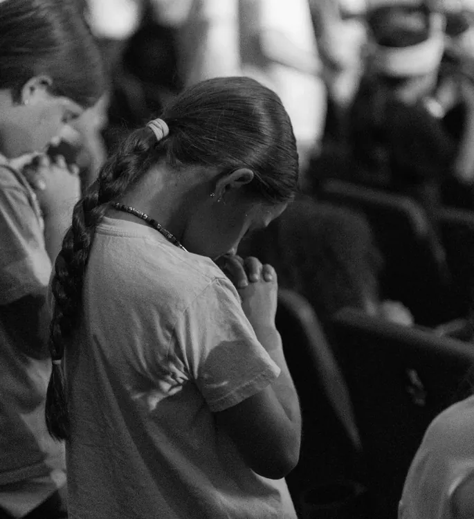 Girl praying with folded hands during worship
