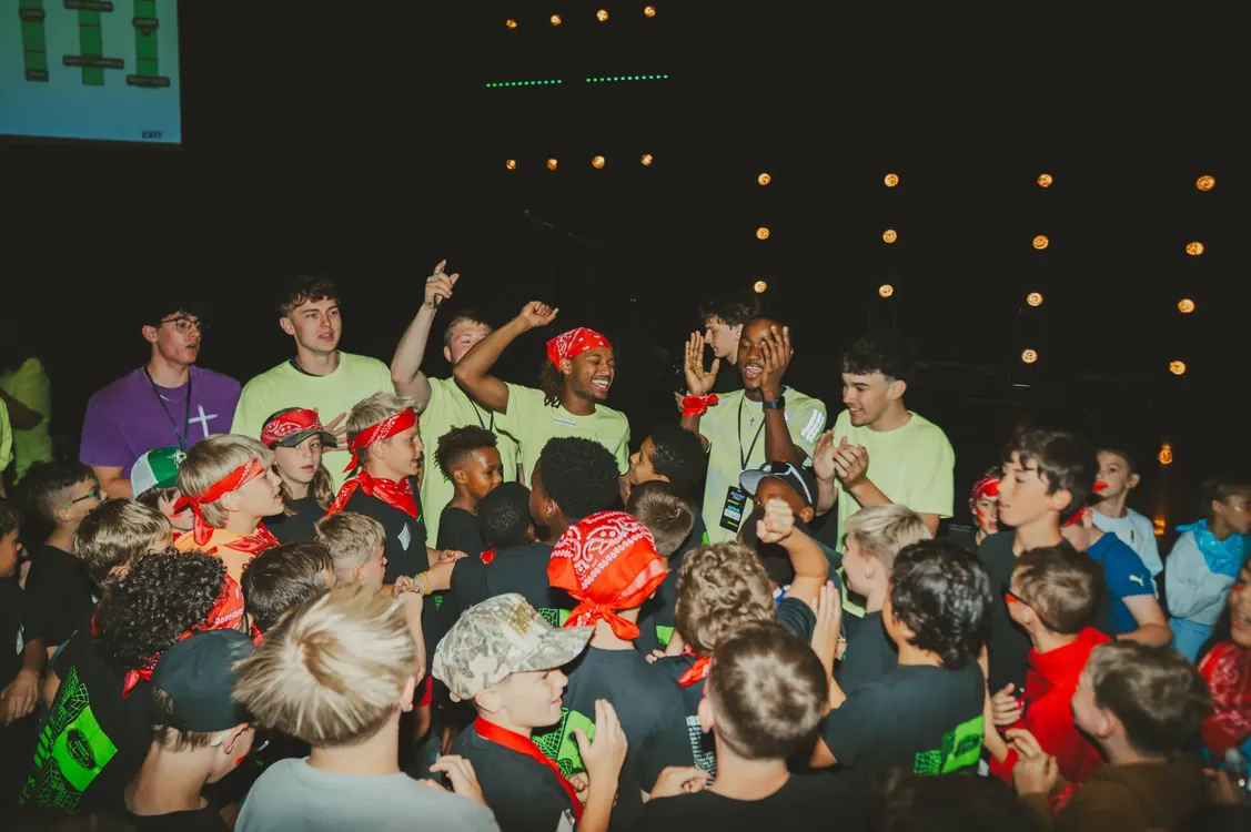 Leaders celebrating with kids in red bandanas at an evening party