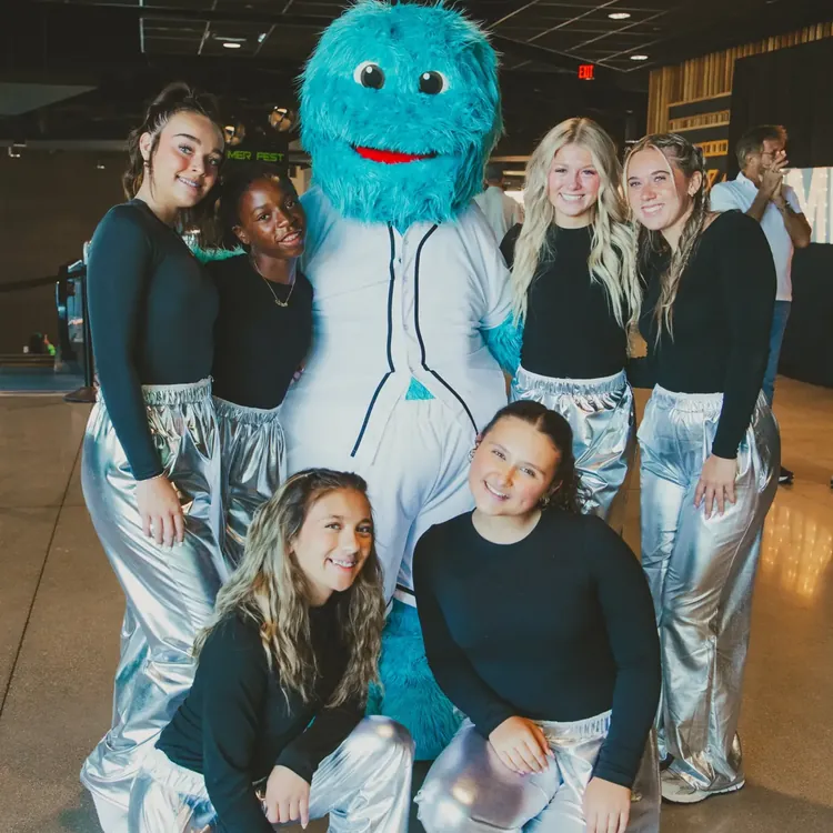 Leaders posing with a blue furry mascot