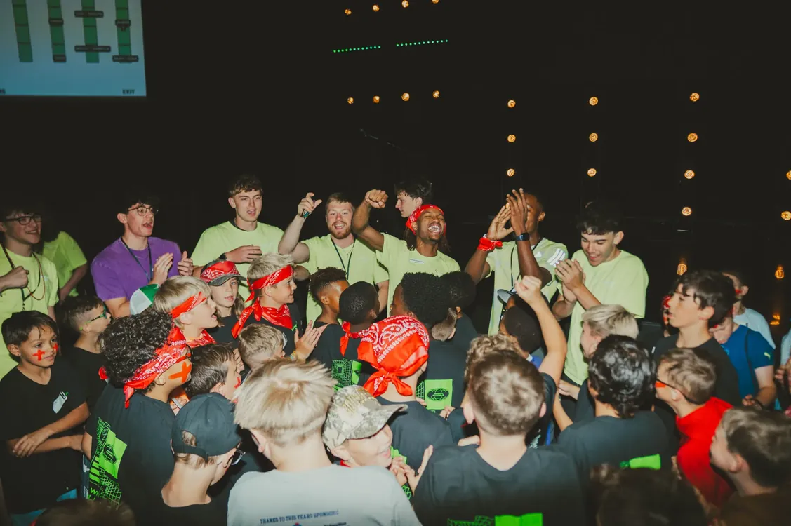Kids and leaders cheering together at an evening party