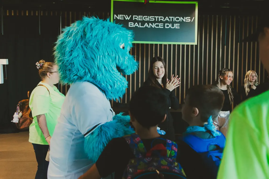 Blue mascot greeting families at check-in