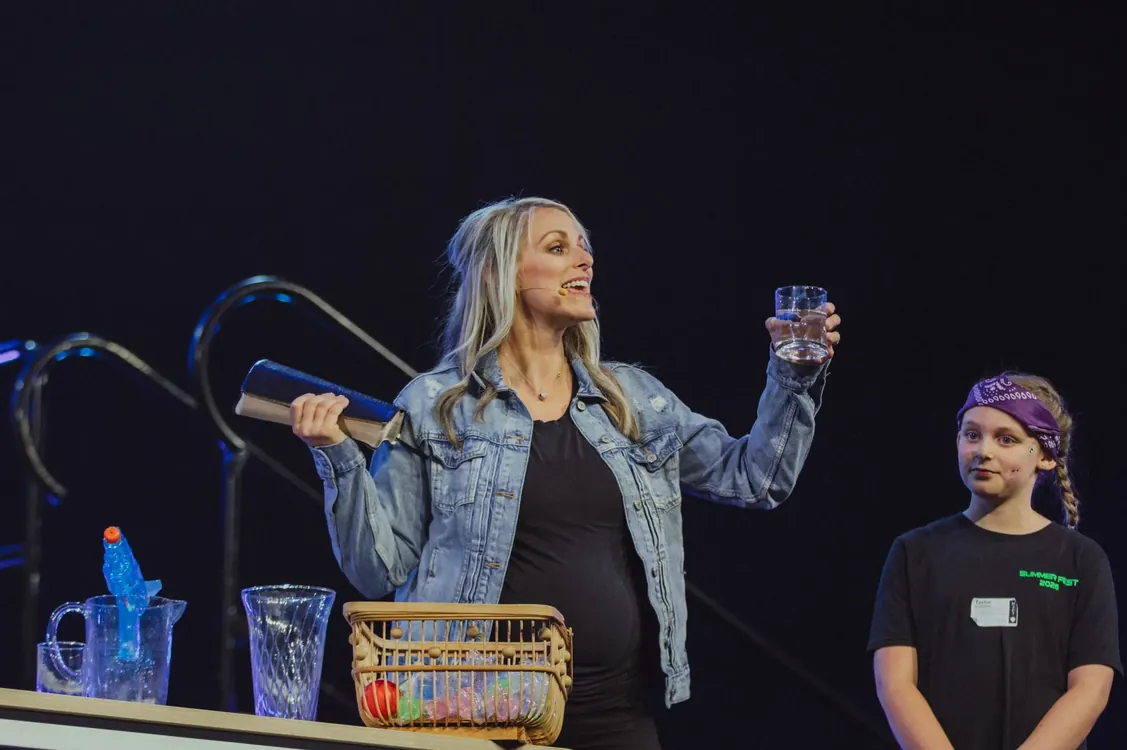 Speaker teaching on stage with a student helper