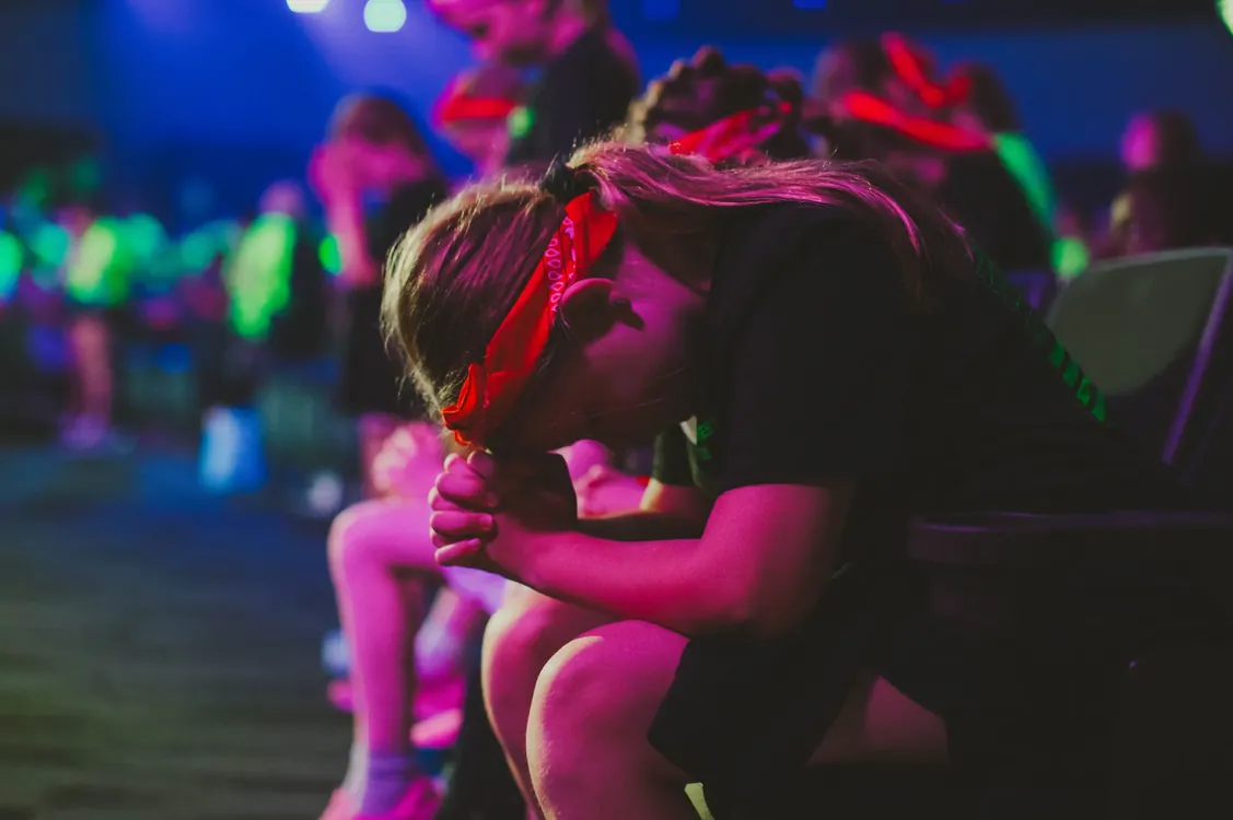 Girl in a red bandana praying in the auditorium