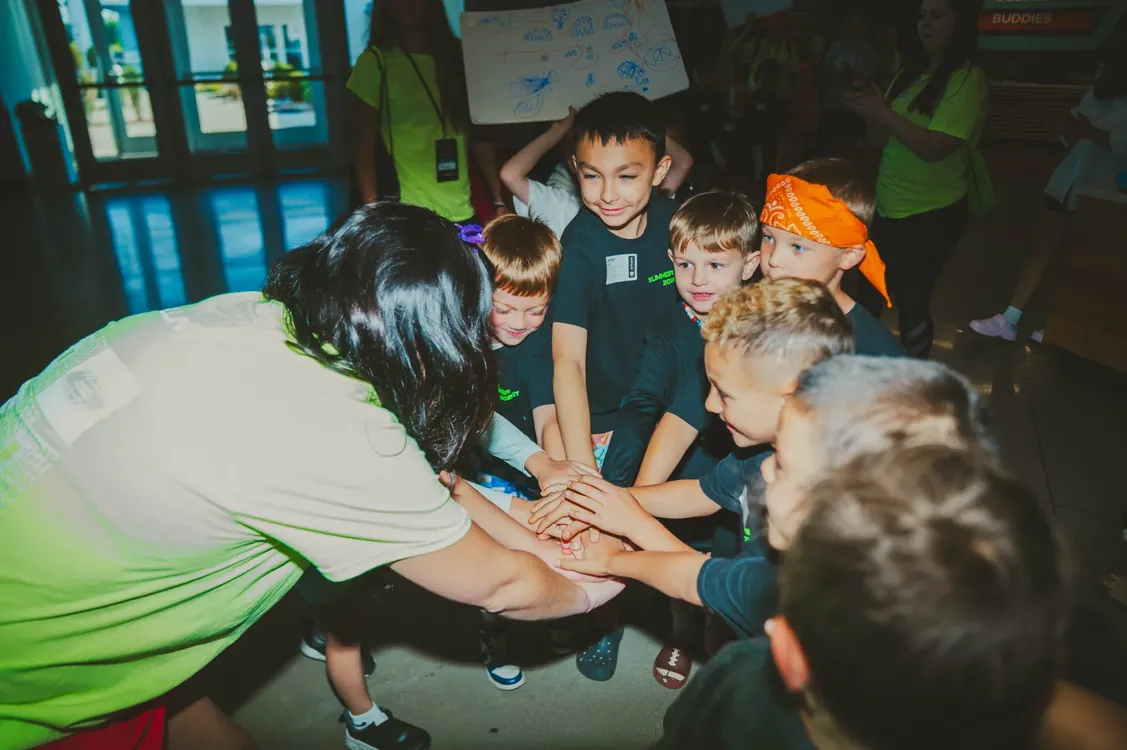 Leader and kids stacking hands in a team huddle