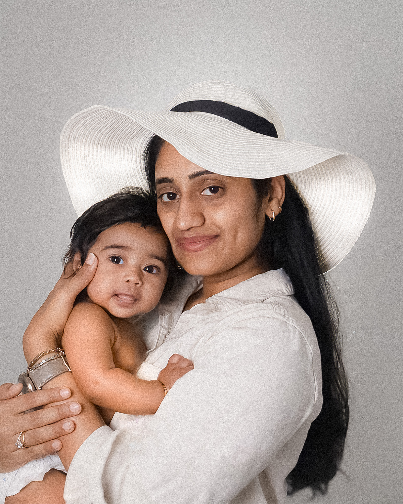 Mother holding her daughter by wearing a hat