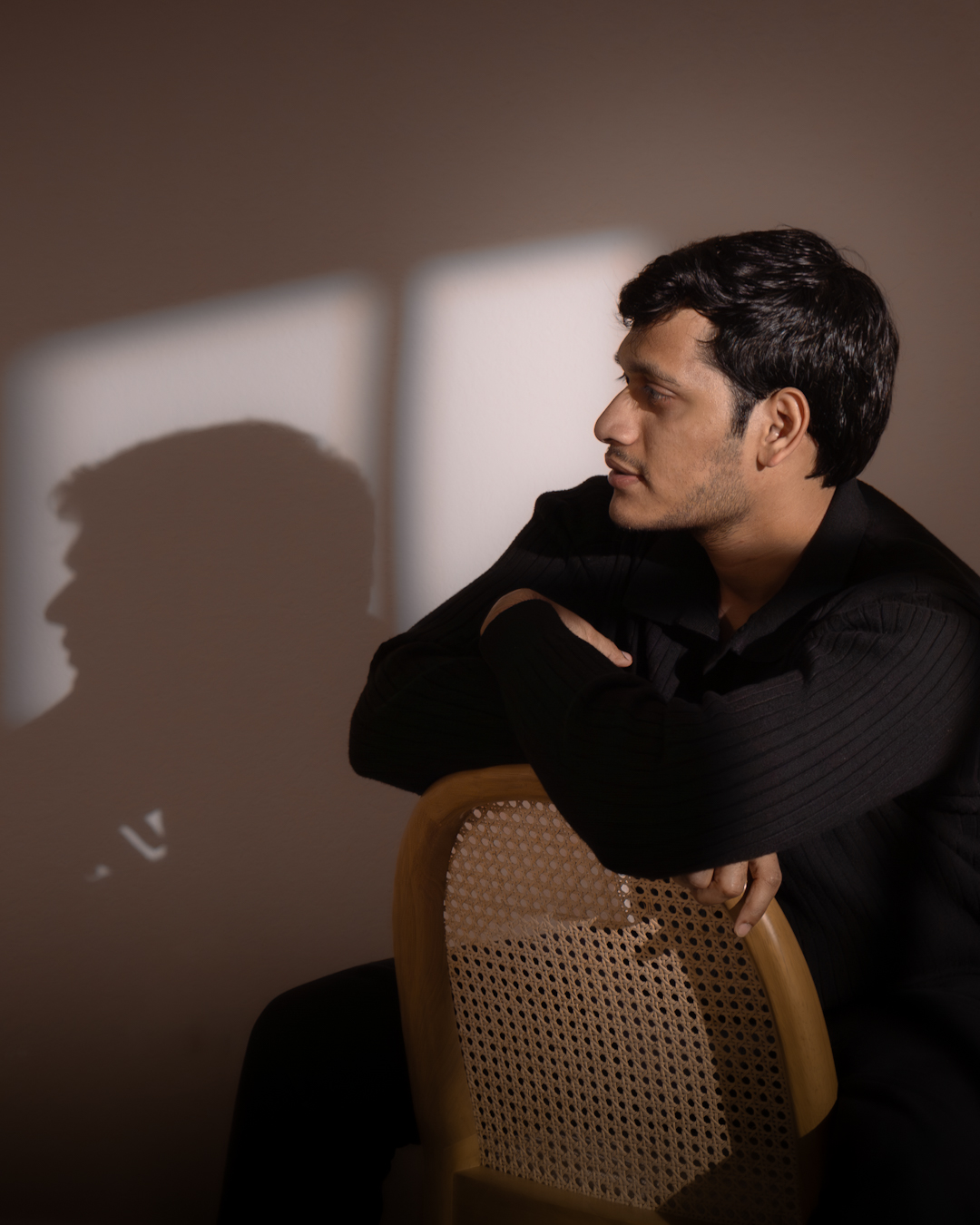 Man sitting on chair with a shadow casting on the wall
