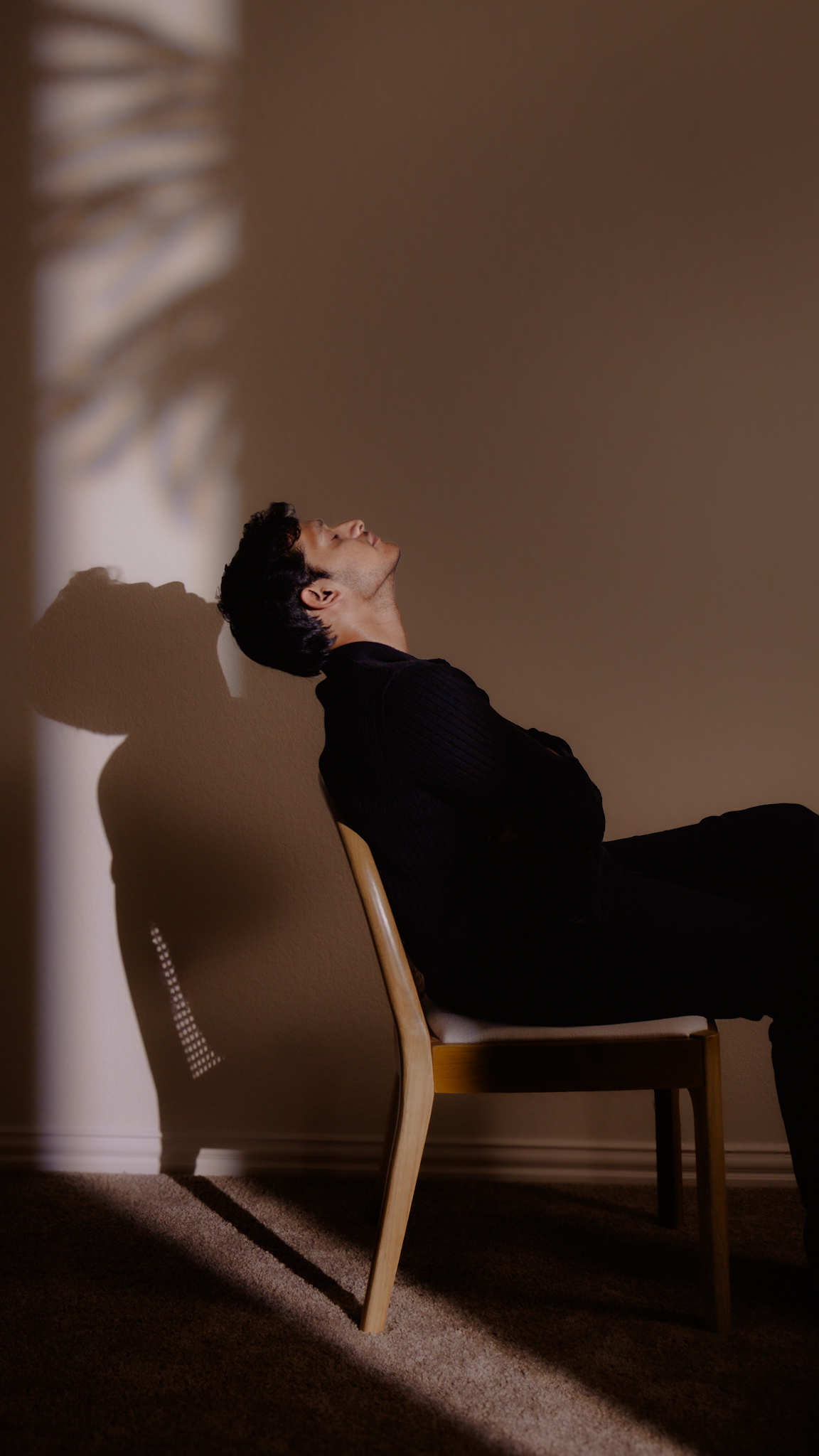 Man sitting on chair with a shadow reflecting on wall
