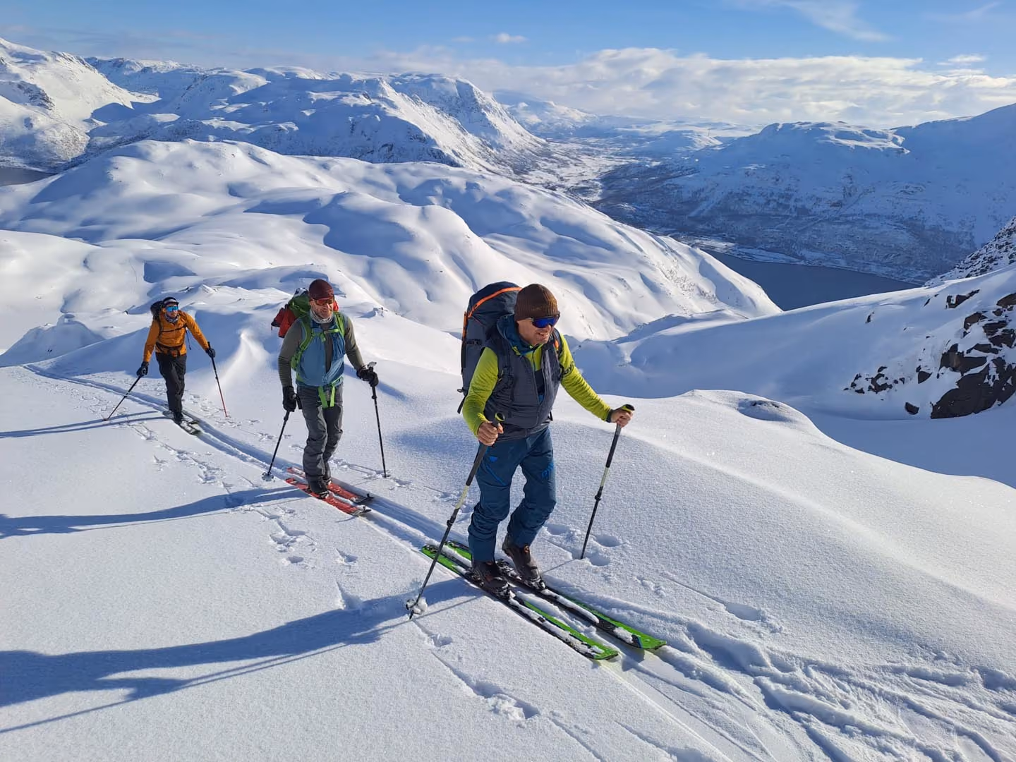 Group of ski tourers walking in single file up a steep snowy slope.