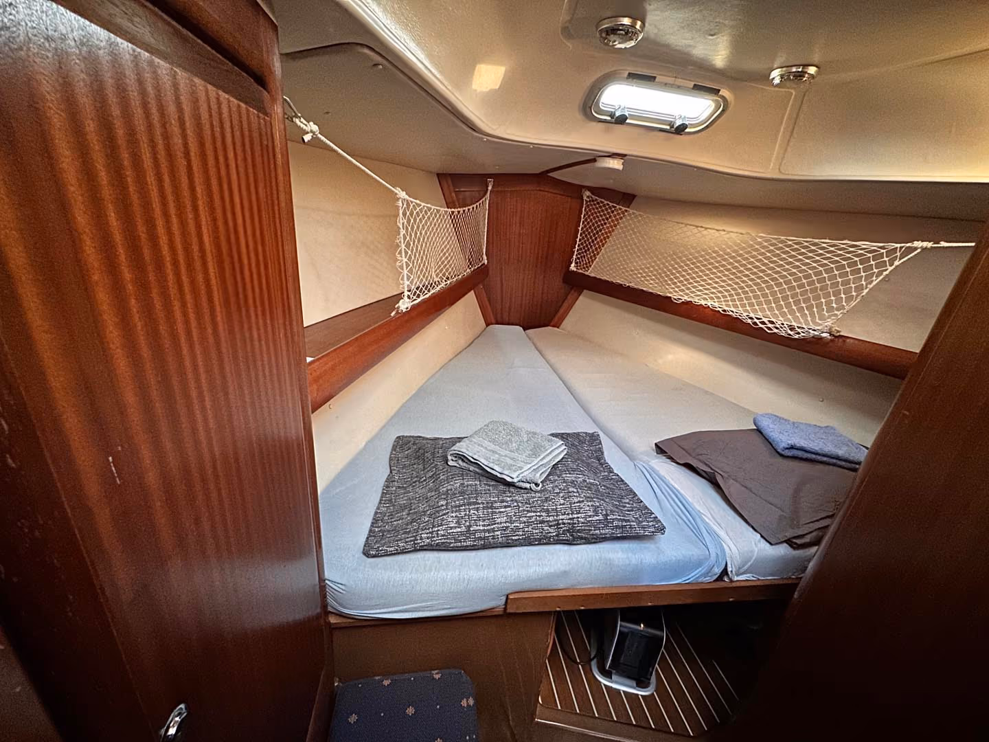 Cozy wooden sleeping berth inside a sailboat with neatly made bedding.