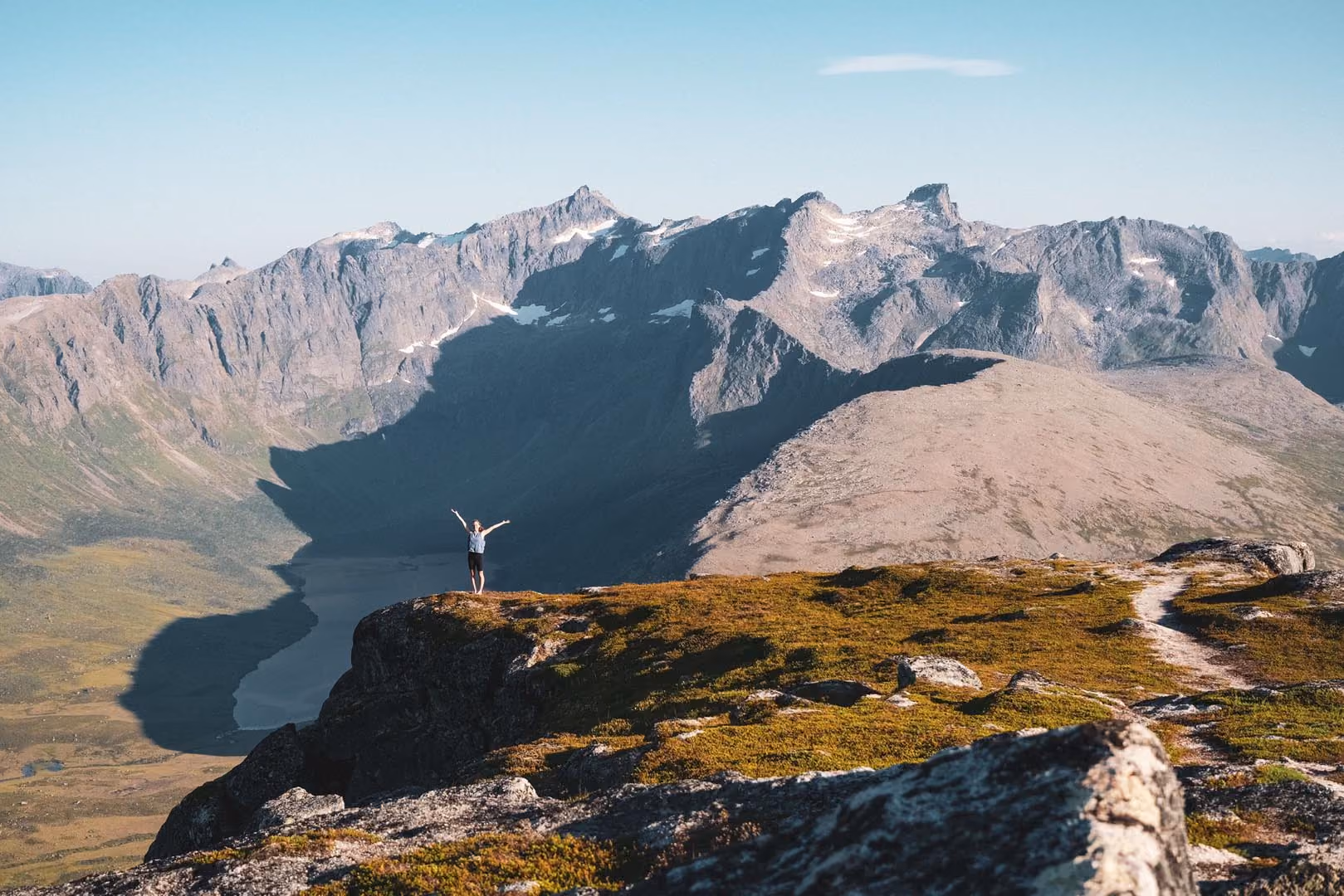 Panoramic view of a dramatic mountain range with sharp, sunlit peaks.