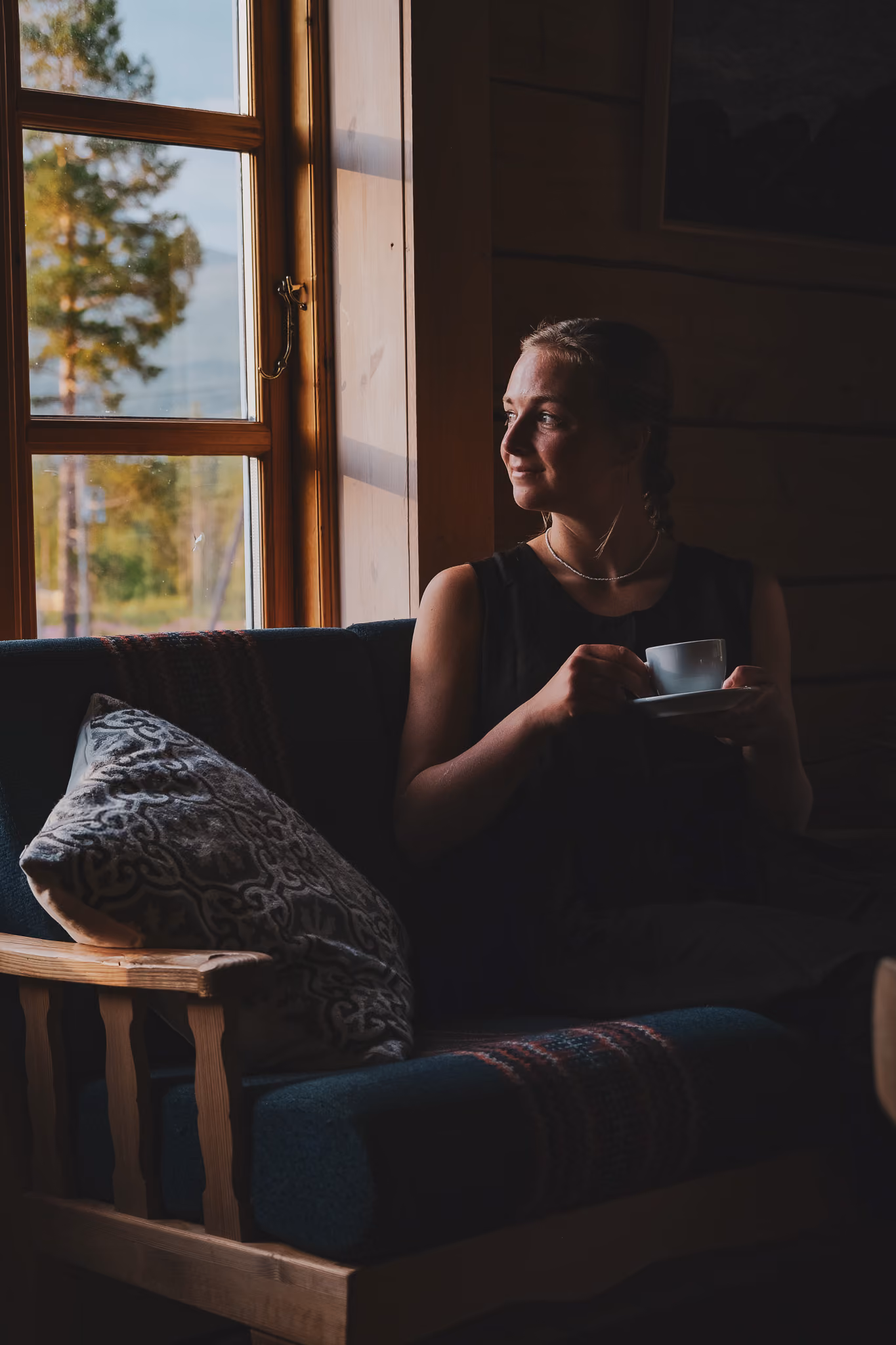 Silhouetted figure sitting near a window with sunlight streaming into a dark room.