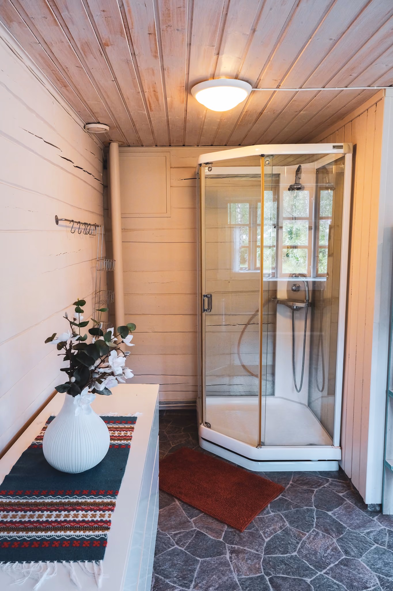 Brightly lit hallway with a small sink and a glass-door shower enclosure.