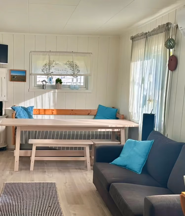 Sunlit living area with a wooden table, sofa, and glass patio doors.