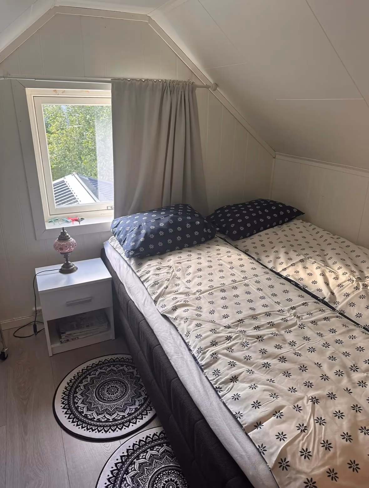Attic bedroom featuring a cozy bed positioned under a sloped ceiling and window.