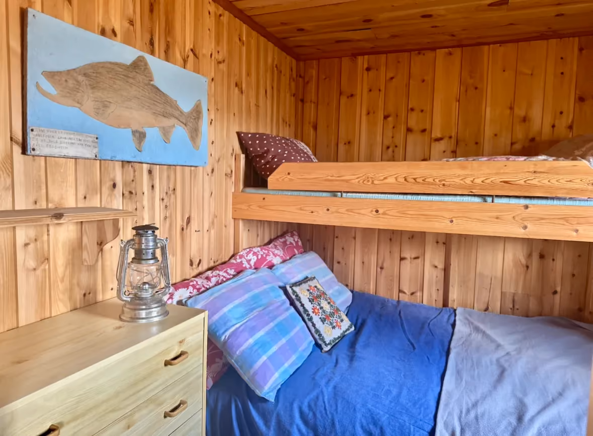 Cozy cabin bedroom with wooden bunk beds and blue bedding.