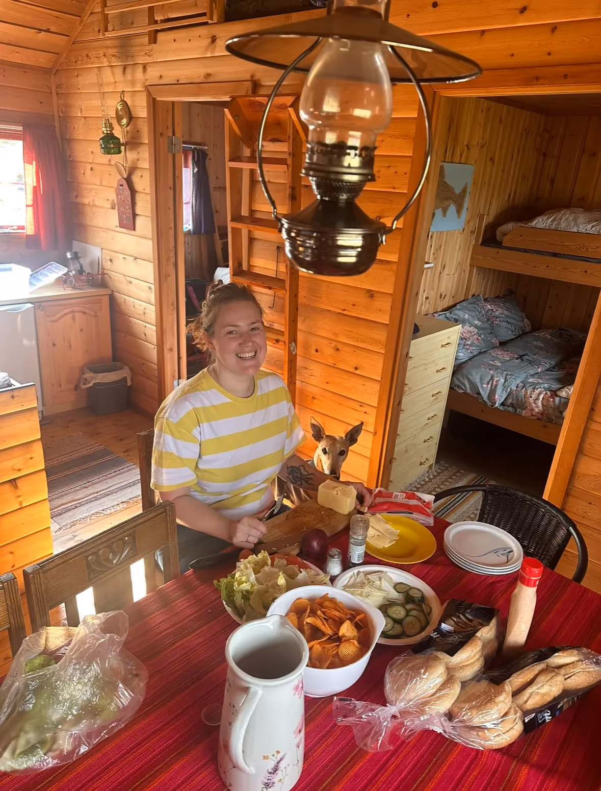 Table set with food, candles, and drinks inside a cozy wooden cabin.