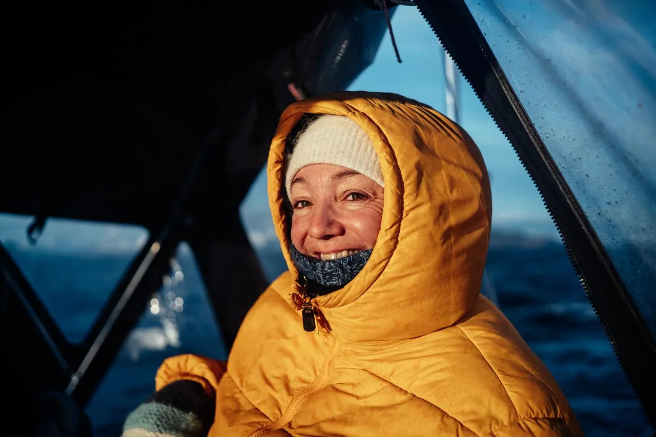 Person in a bright yellow hooded coat sitting inside a boat cockpit.