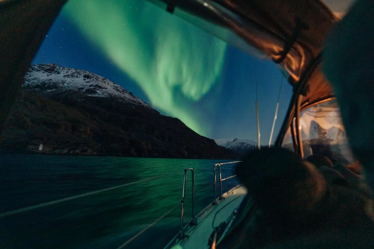 Brilliant green aurora borealis swirling across the night sky above a boat deck.