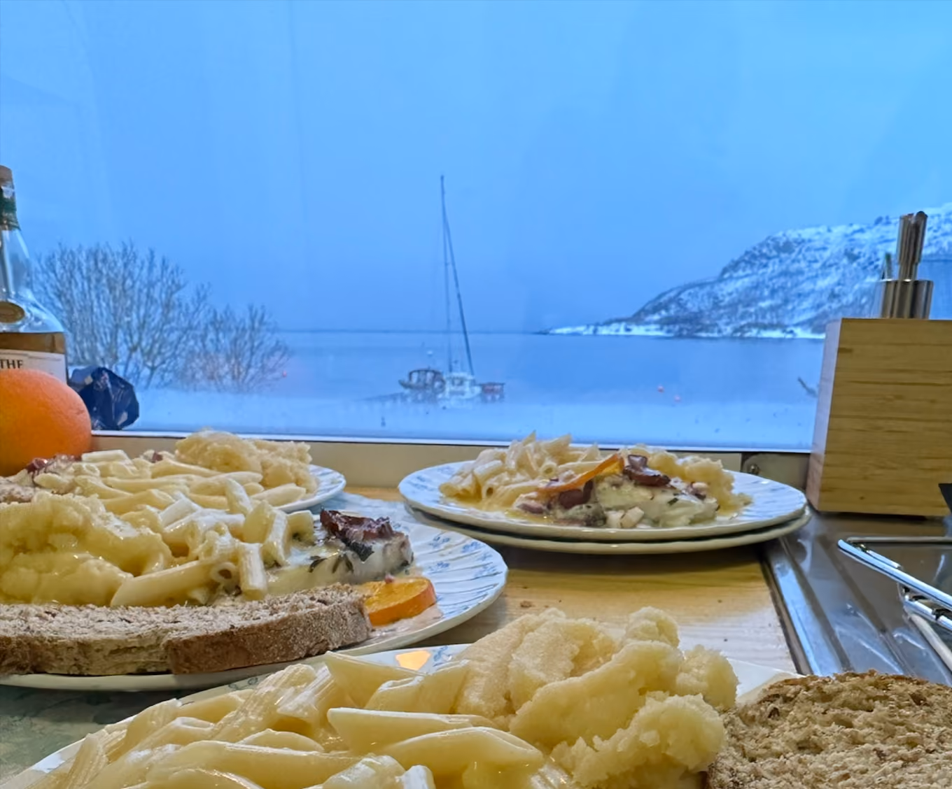 Table filled with platters of food in front of a window with a sea view.