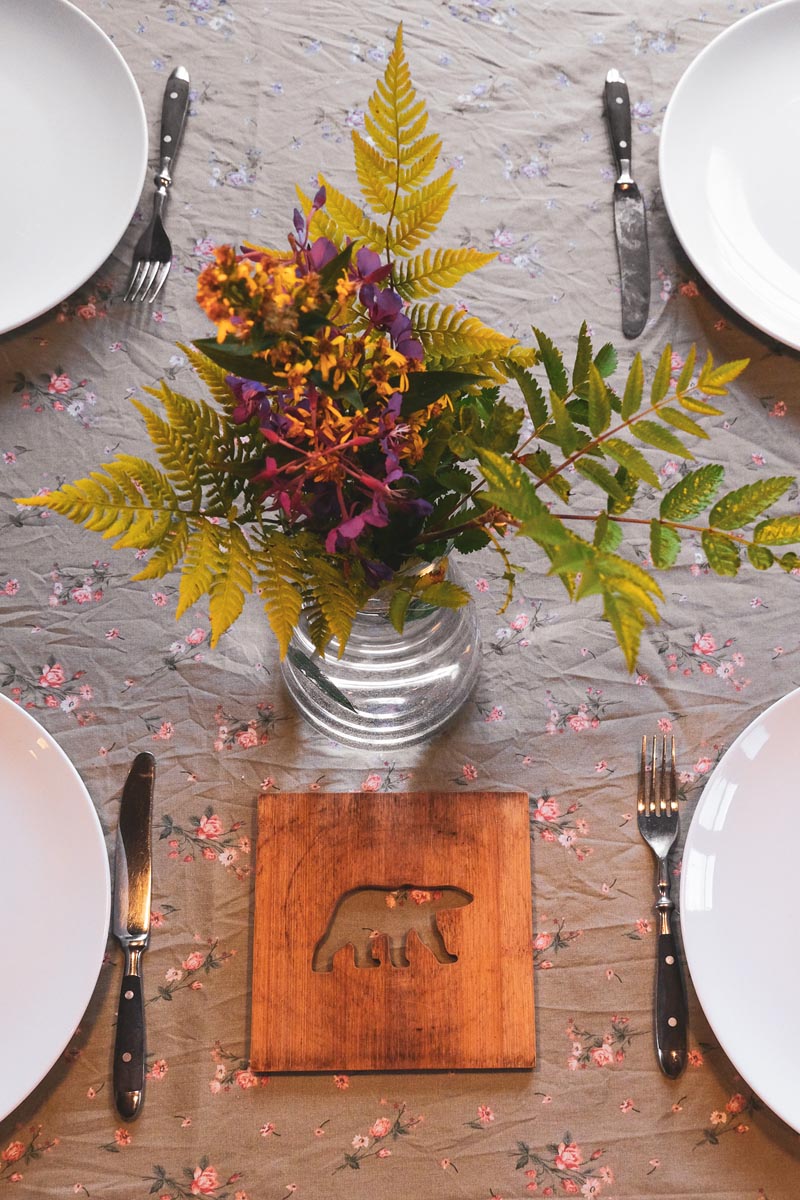 Top-down view of a dining table setting with plates, cutlery, and a floral centerpiece.