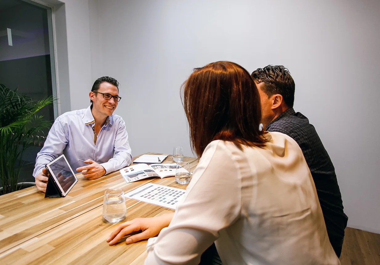 Drie medewerkers van Roozenburg Dakwerken aan een vergadertafel in hun kantoor in Rijkevorsel