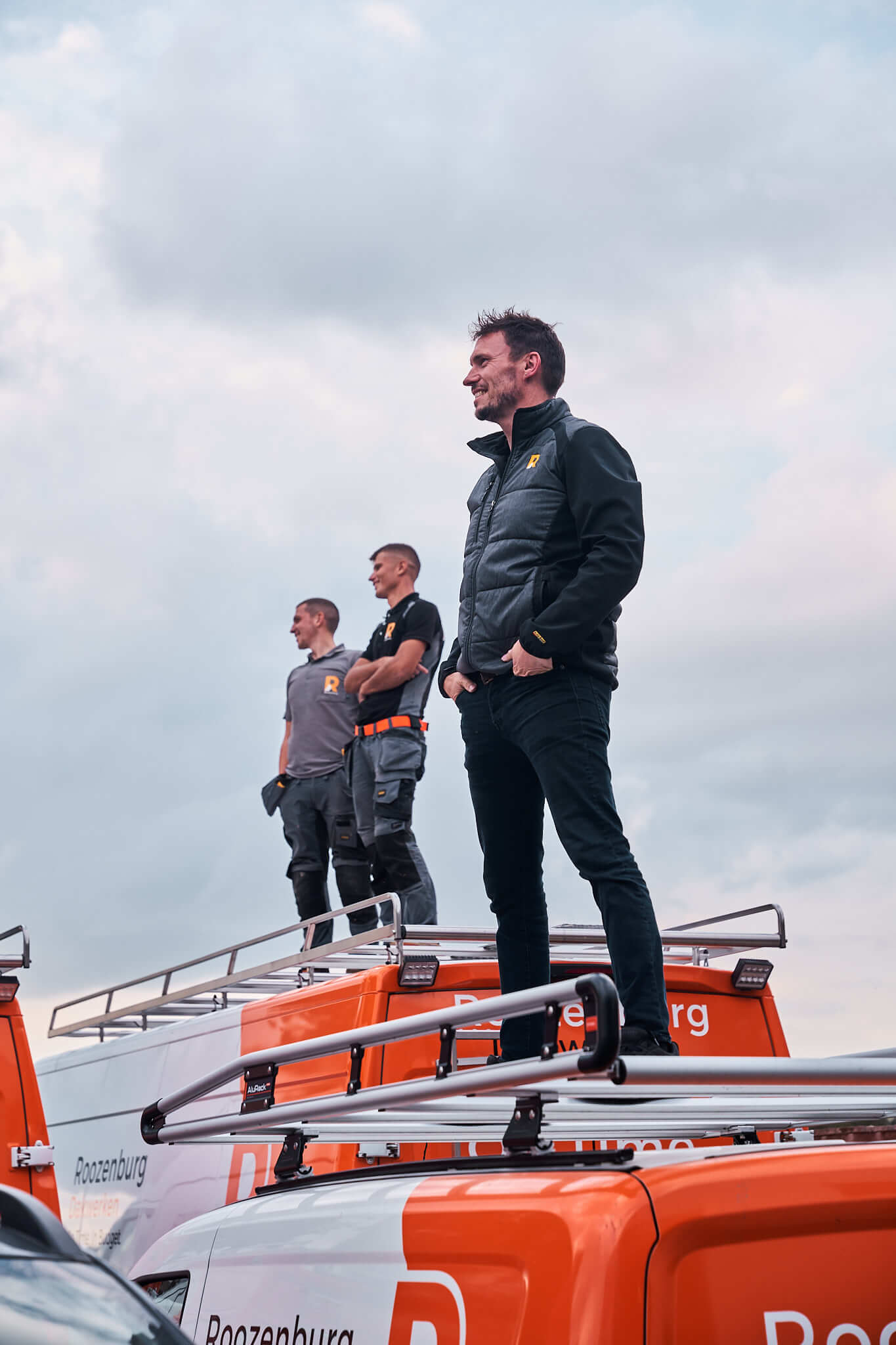 Drie medewerkers van Roozenburg Dakwerken staat op het dak van hun werkbus in Rijkevorsel