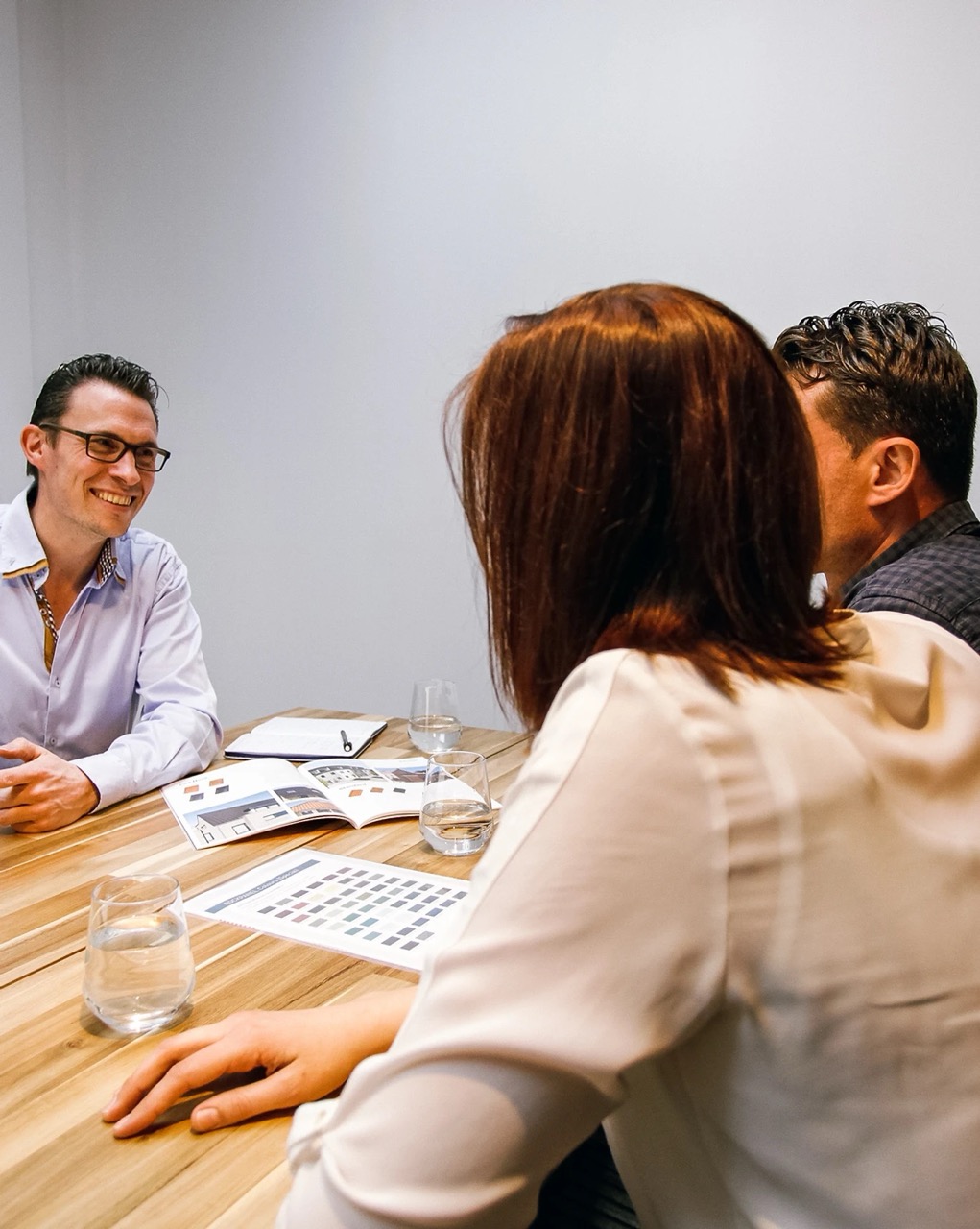 Drie medewerkers van Roozenburg Dakwerken aan een vergadertafel in hun kantoor in Rijkevorsel