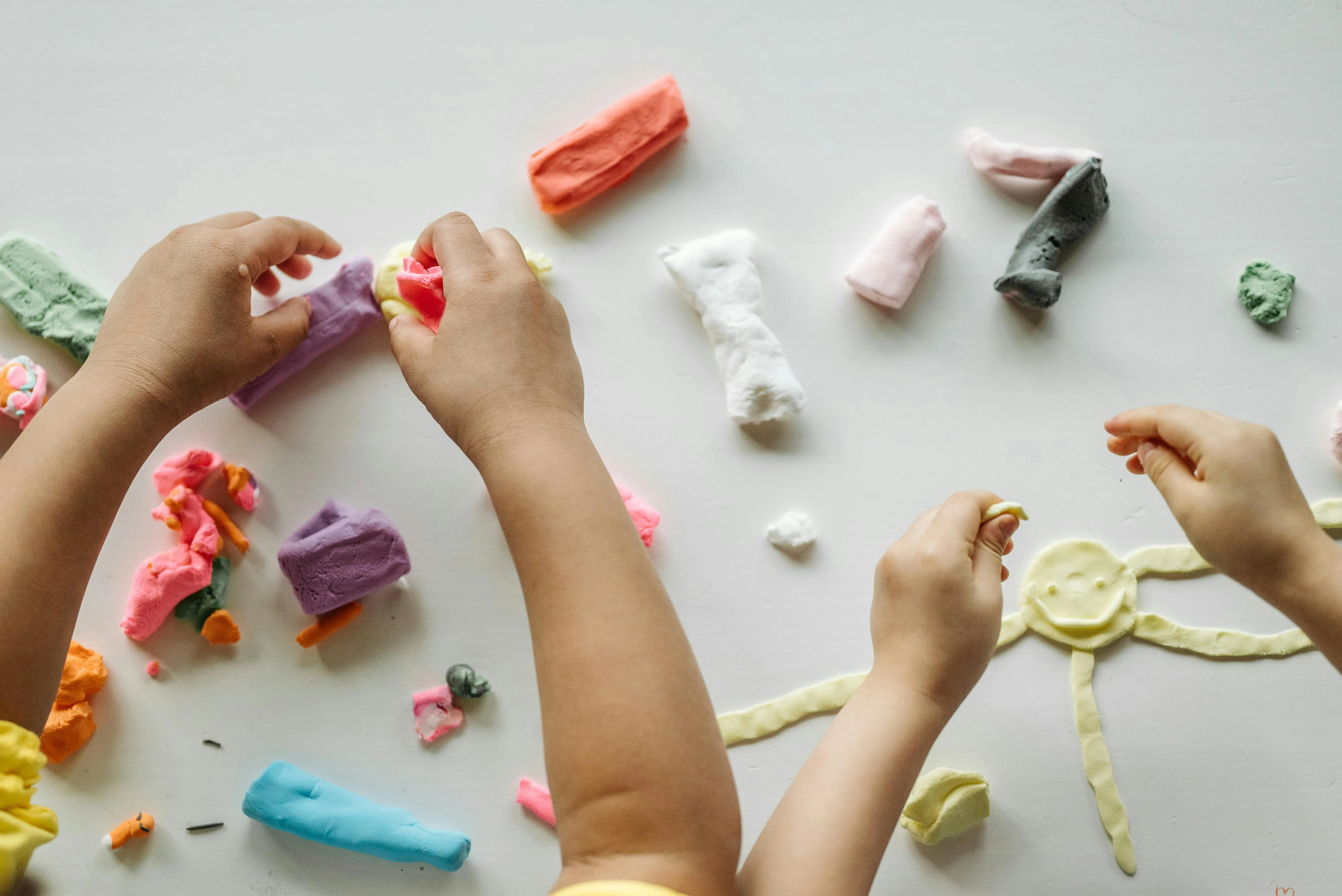 Mains d'enfants qui font une activité manuelle avec de la pâte à modeler.