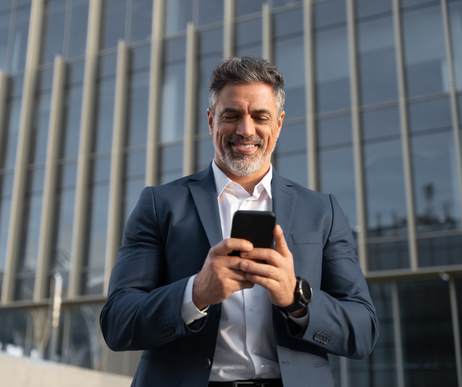 Mann mit Smartphone in der Hand vor einem Gebäude.