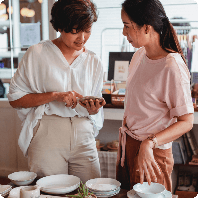 two persons standing next to each other and looking at a phone