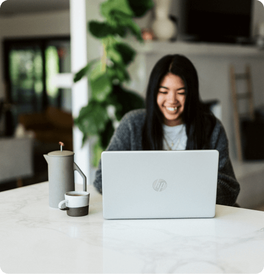 a woman standing at the desk and looking at a laptop
