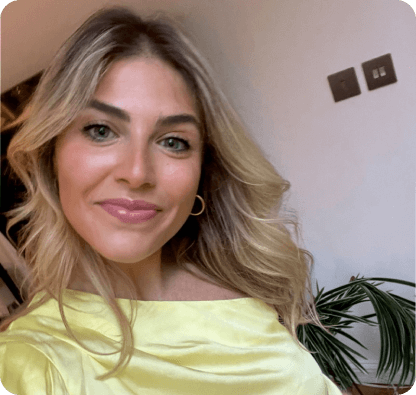 Tash dressed in a yellow top smiling at the camera