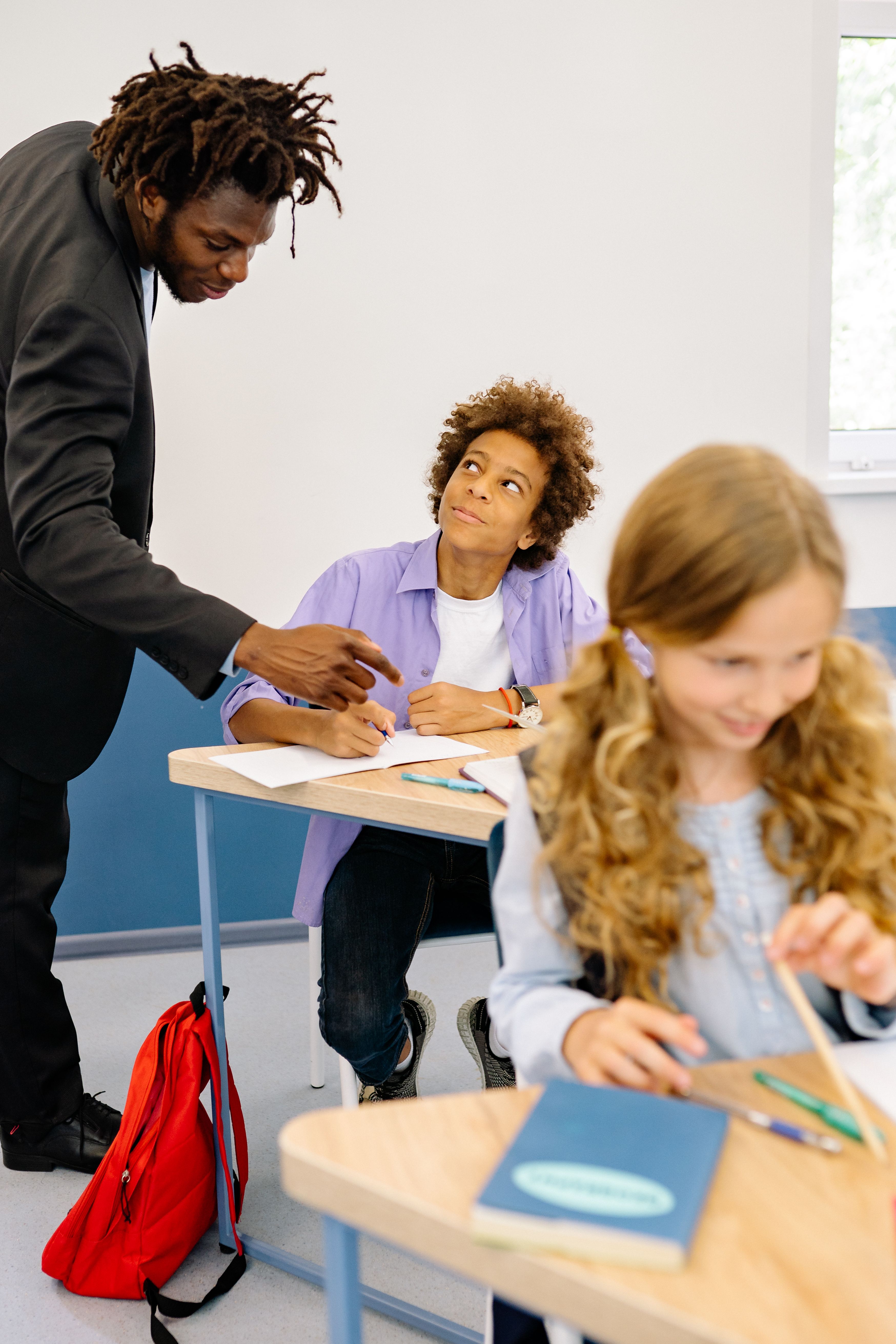 Teacher pointing to a student's work at a classroom desk