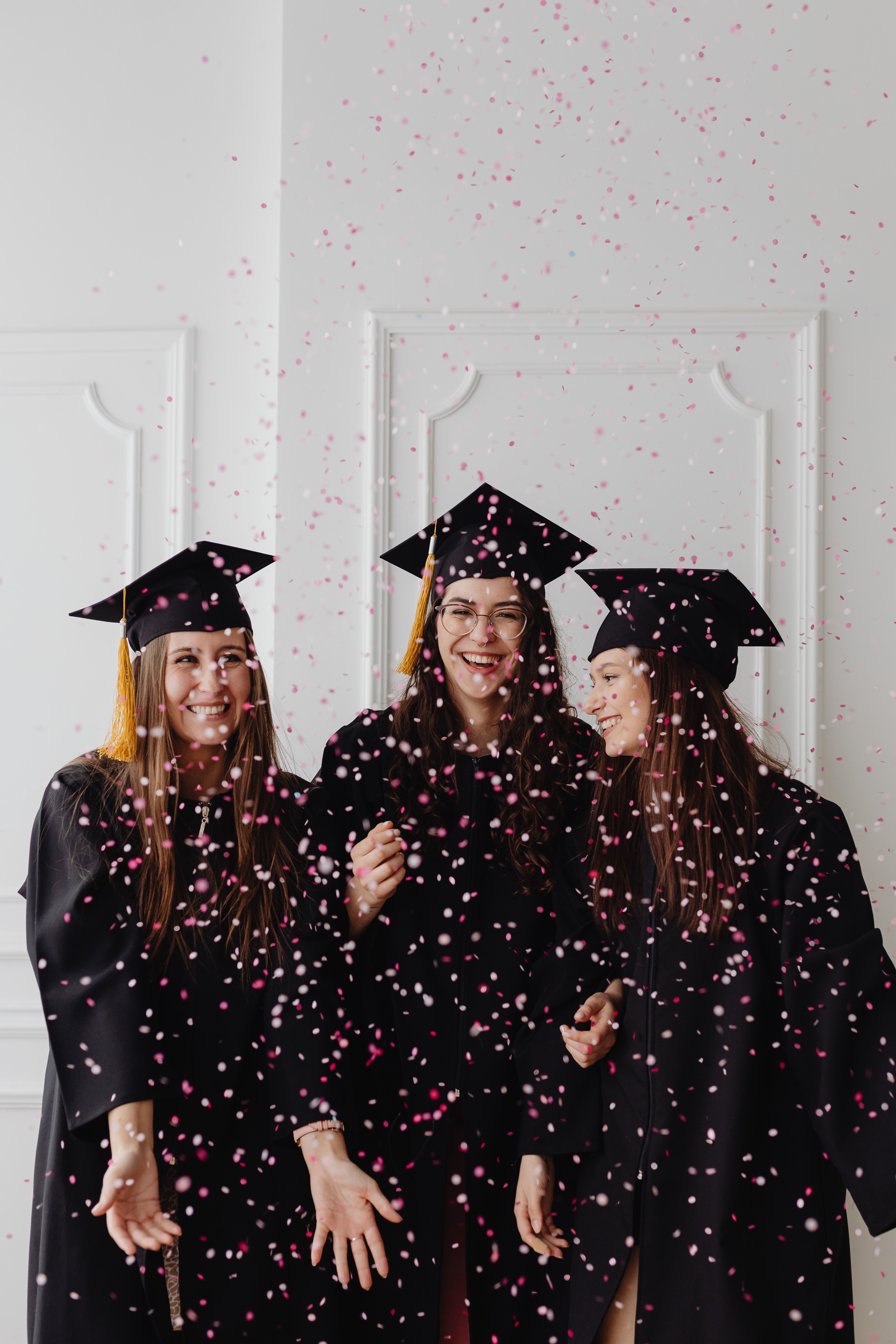Graduates tossing their caps in the air in front of a school building