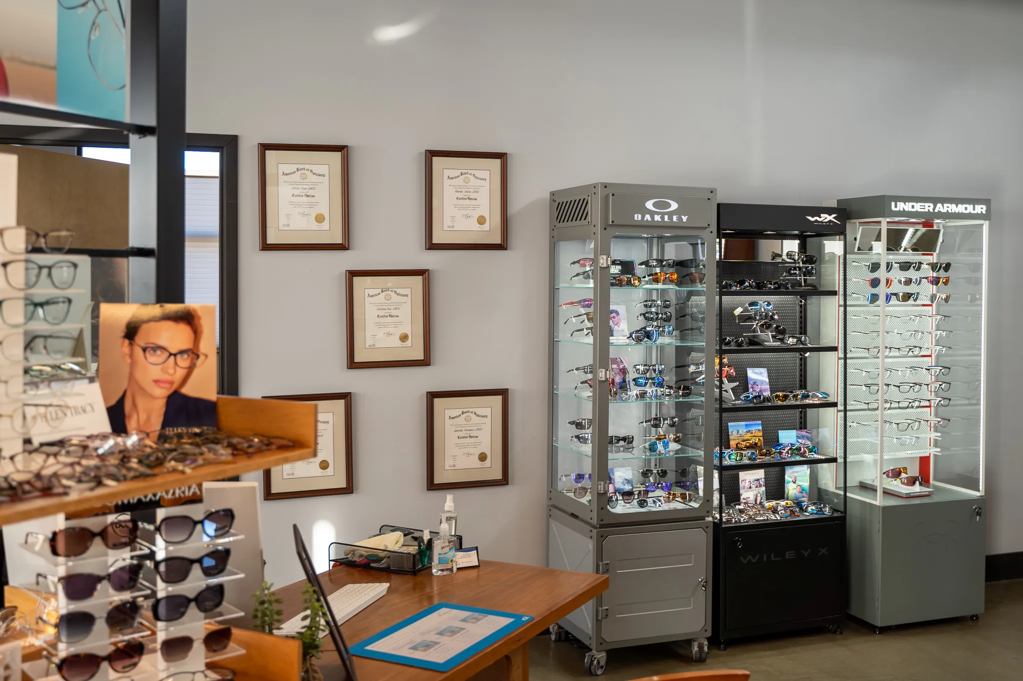 Glasses in a display case with diplomas hanging on the wall