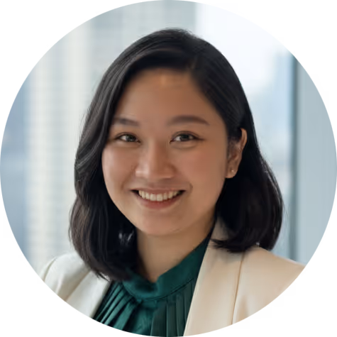 Smiling woman with shoulder-length black hair wearing a white blazer and green blouse.
