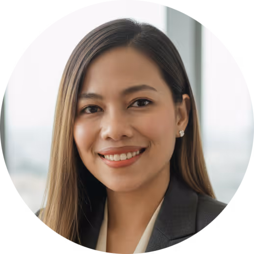 Smiling woman with long hair wearing a black blazer and white blouse in a bright office.