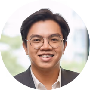 Young man wearing glasses and braces, smiling, dressed in a dark blazer and white shirt.