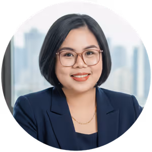 Smiling woman with glasses and short black hair wearing a navy blazer with cityscape background.