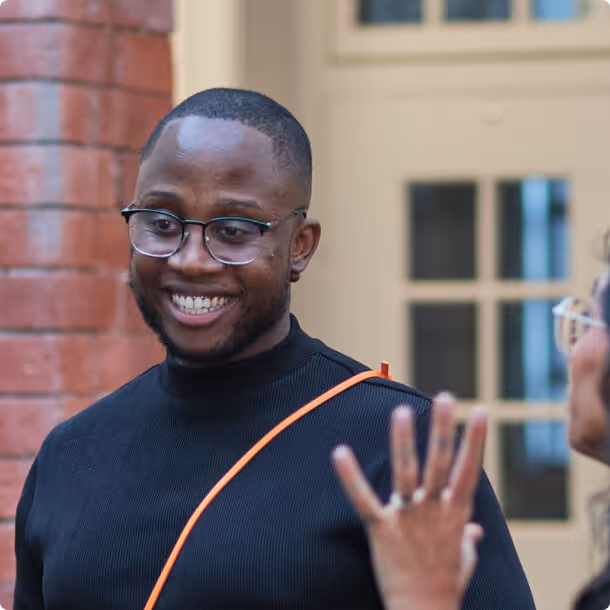 A man in a black shirt and glasses making a peace sign.