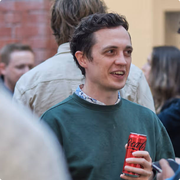 A man in a green sweater holding a can of beer.