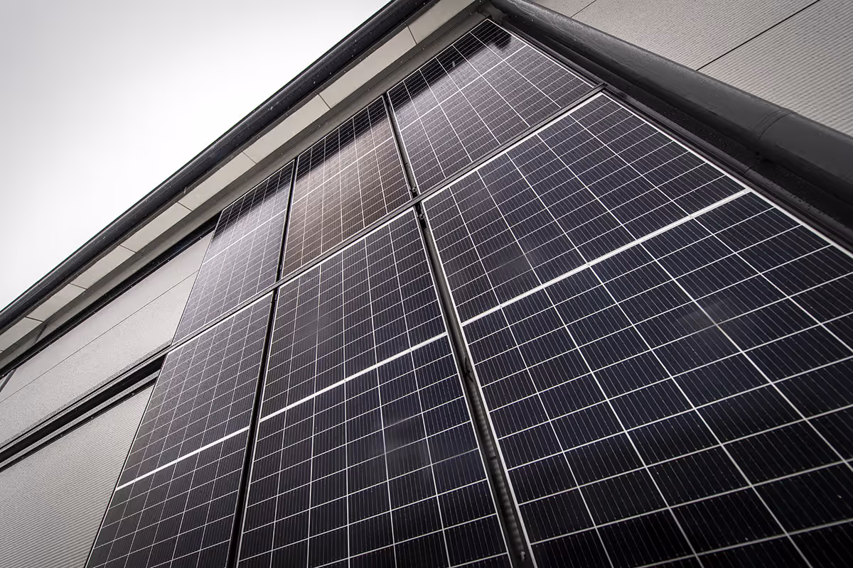 Aurinkopaneelit kiinnitettynä rakennuksen julkisivuun ylhäältä päin kuvattuna.