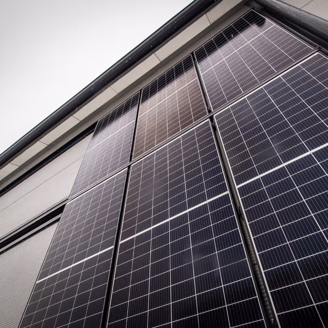 Aurinkopaneelit asennettuna rakennuksen seinälle ylöspäin kuvattuna RAULI WALL kiinnikkeet.